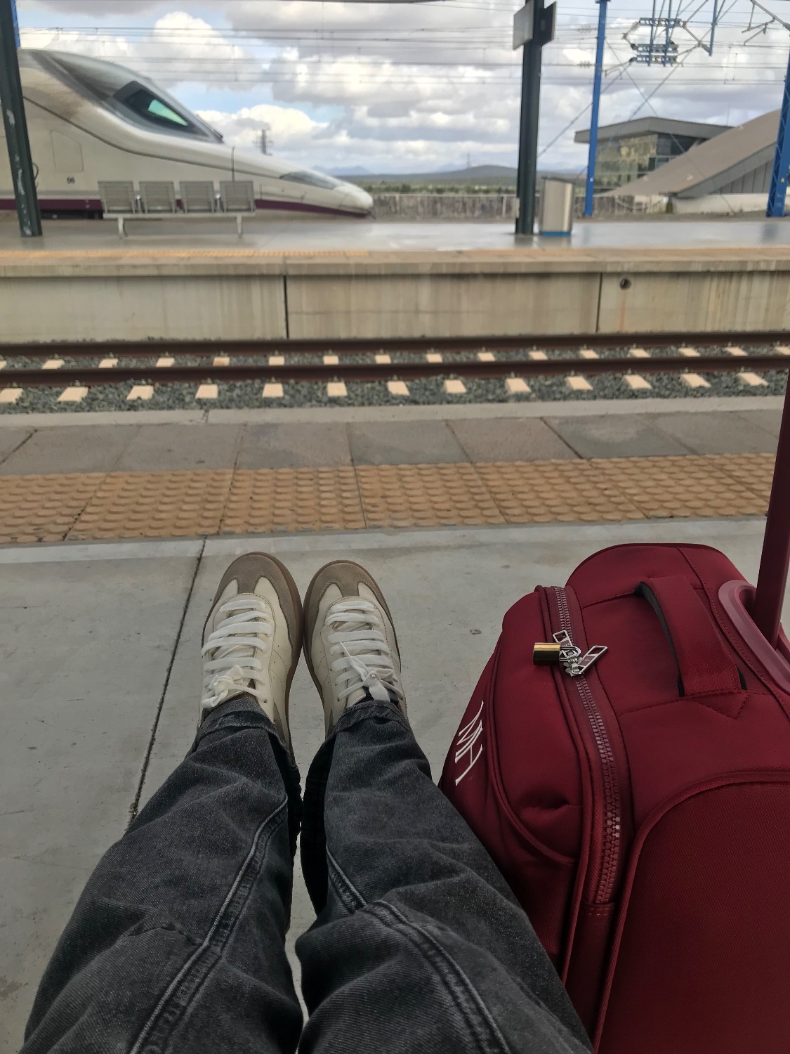 Maleta de viaje en el andén de una estación, con un tren de alta velocidad de fondo